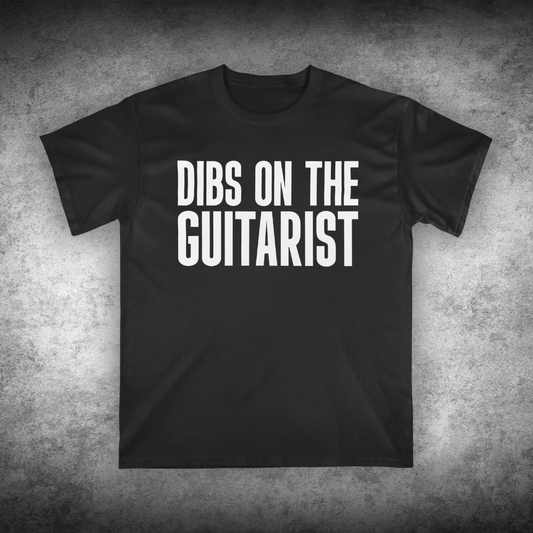 Black t-shirt with 'DIBS ON THE GUITARIST' text on a textured gray background