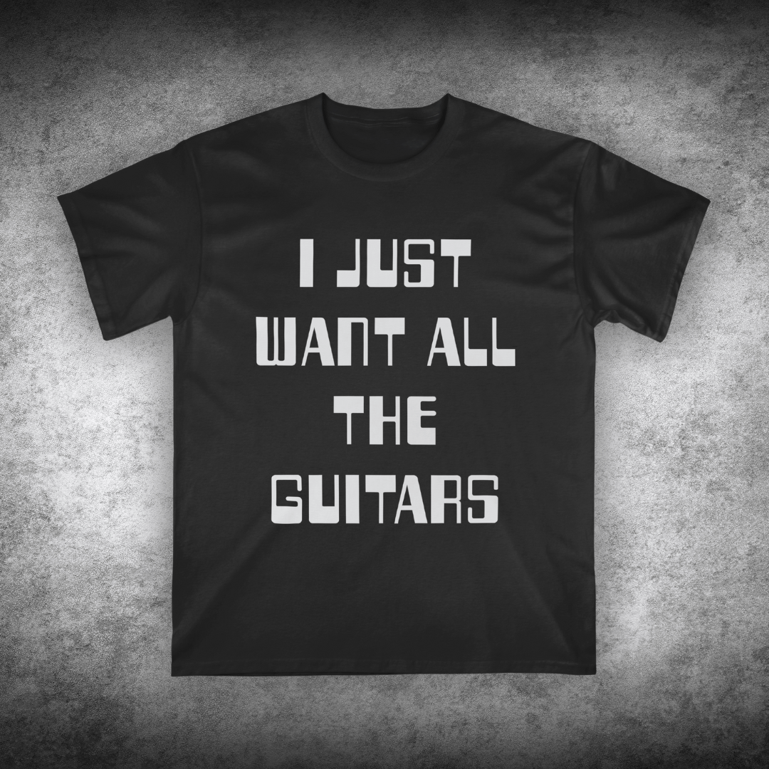 Black t-shirt with white text 'I JUST WANT ALL THE GUITARS' on a textured gray background