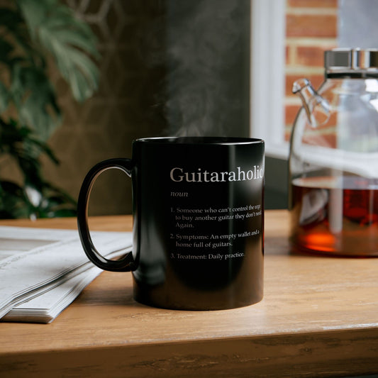 Black mug with 'Guitaraholic' definition on a wooden surface with a blurred background